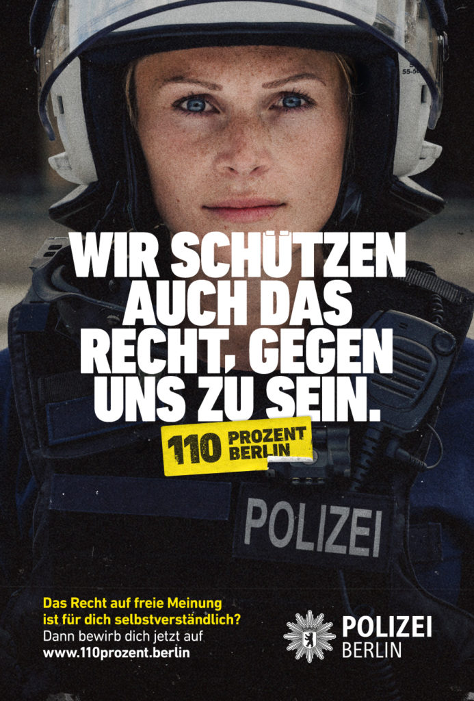 Polizistin mit Helm, Schrift: Wir schützen auch das Recht gegen uns zu sein